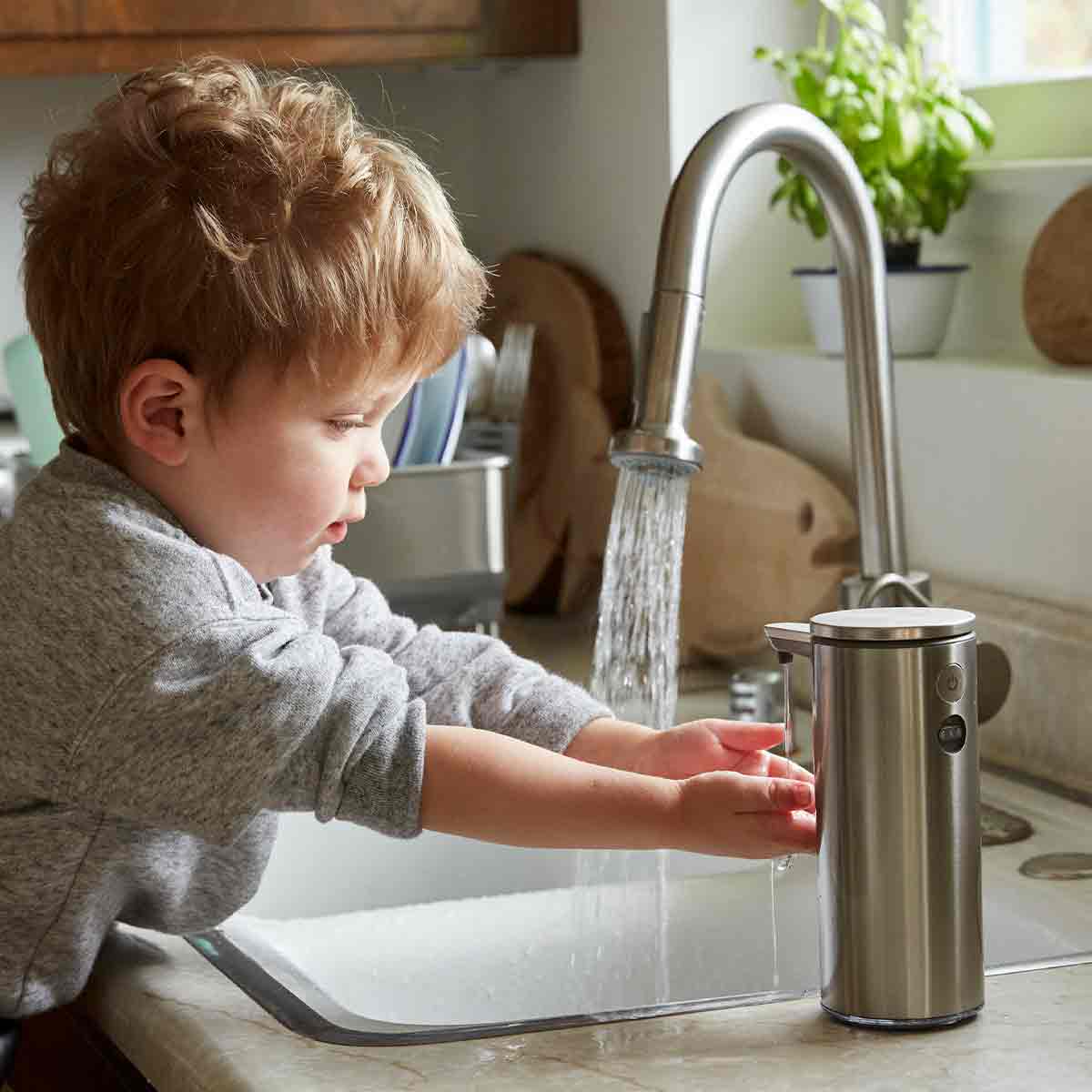 rechargeable liquid soap sensor pump - brushed finish - boy using pump in kitchen